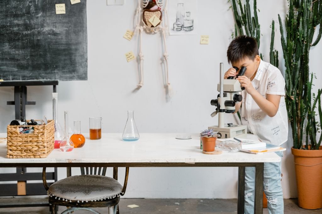 A young boy in a laboratory examining samples through a microscope for educational purposes.